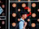 A man with a backpack walks past a storefront displaying multiple bitcoin symbols and an advertisement for bitcoin ATMs in Nicosia