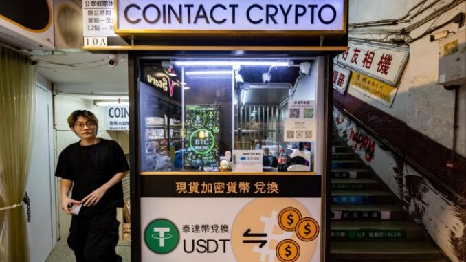 A picture of a man walking beside a cryptocurrency exchange booth in Hong Kong 