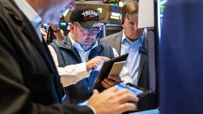 A trader wearing a Trump hat works on the floor of the New York Stock Exchange