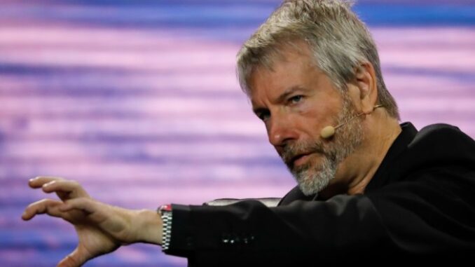 Michael Saylor raises his left hand as he makes a point. He is wearing a microphone