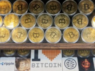 Rows of gold-coloured bitcoin tokens displayed in a window, with signage below showcasing various cryptocurrency logos