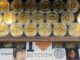 Rows of gold-coloured bitcoin tokens displayed in a window, with signage below showcasing various cryptocurrency logos